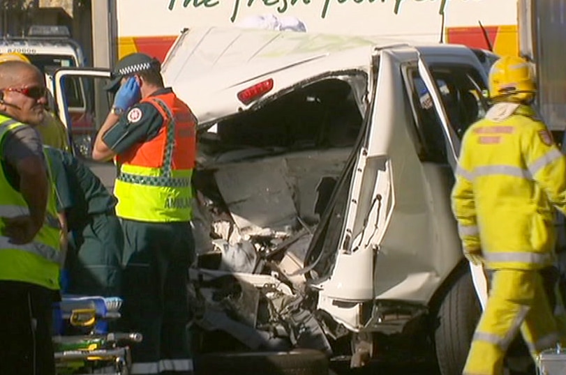 Emergency crews around a smashed white van in front of a Woolworths truck.