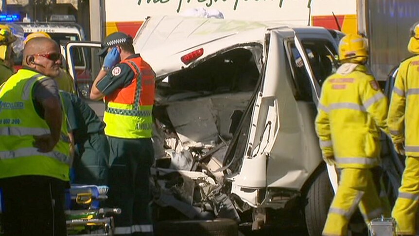 Emergency crews around a smashed white van in front of a Woolworths truck.