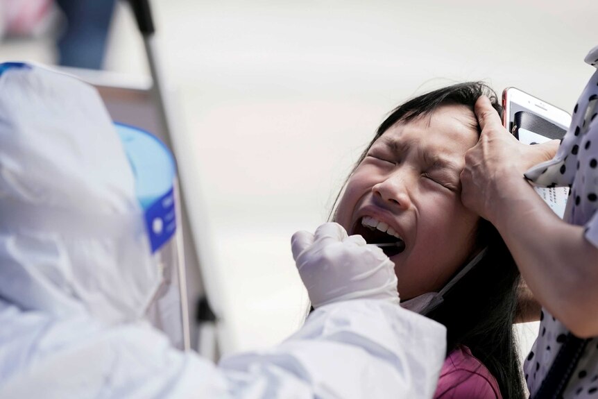 A child reacts with her eyes closed while undergoing nucleic acid testing in Wuhan.