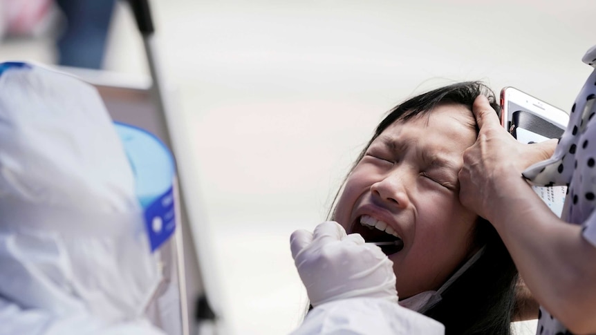 A child reacts with her eyes closed while undergoing nucleic acid testing in Wuhan.