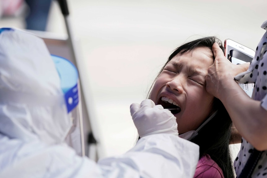 A child reacts with her eyes closed while undergoing nucleic acid testing in Wuhan.