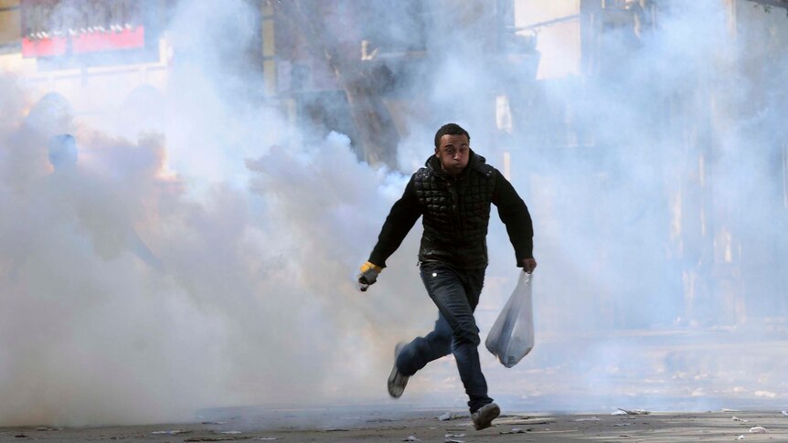 A protester escapes a cloud of tear gas during clashes with security forces near the Interior Ministry in Cairo.