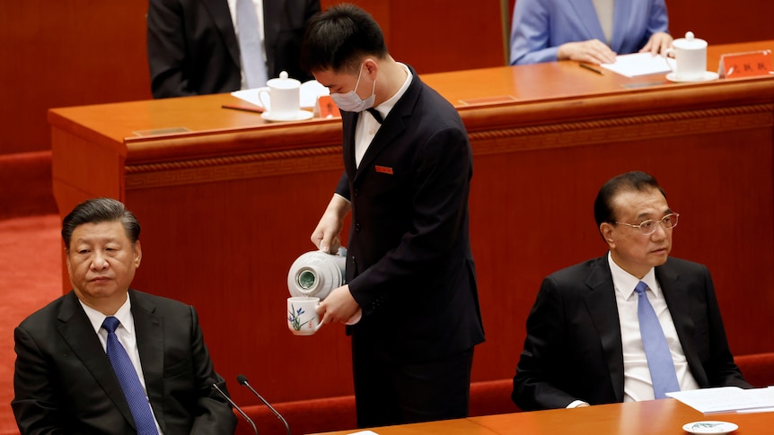 An attendant serves tea in between Chinese President Xi Jinping and Premier Li Keqiang.