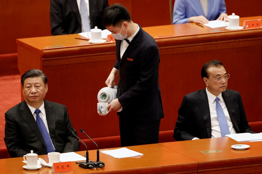 An attendant serves tea in between Chinese President Xi Jinping and Premier Li Keqiang.