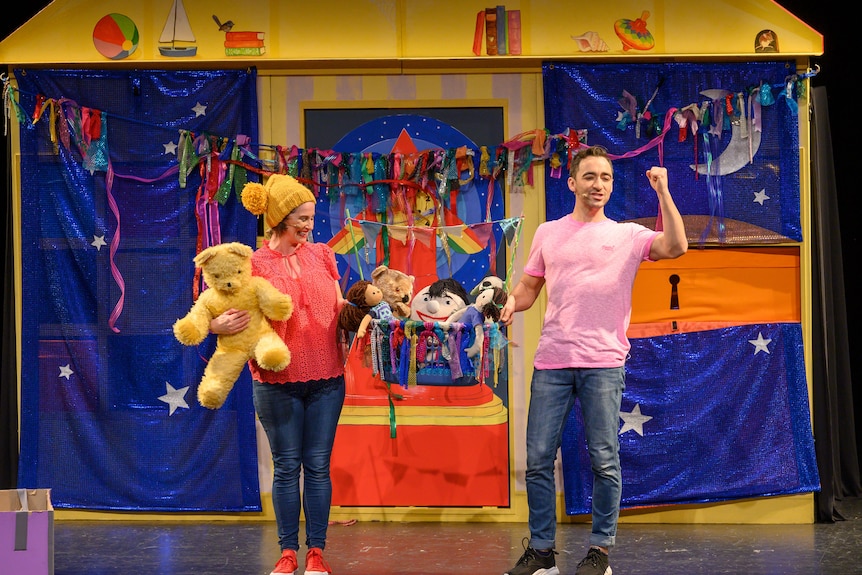 Play School presenters Emma and Matt performing a live show in front of a house prop and holding toys