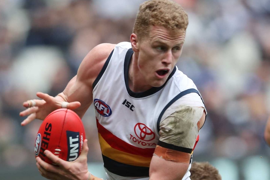 Adelaide Crows player Reilly O'Brien runs away from a pack of Carlton players.