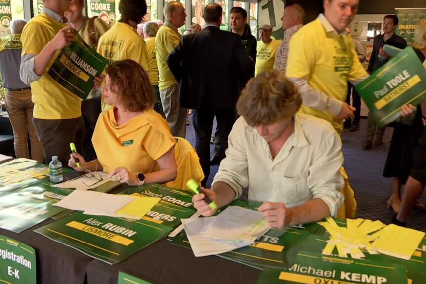 A crowd of people wearing bright colours at work in a volunteer centre for a political campaign.
