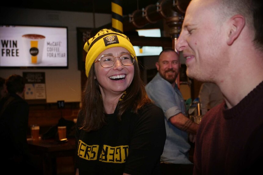 Kim and Dane laugh while watching the Collingwood vs Richmond game at the pub