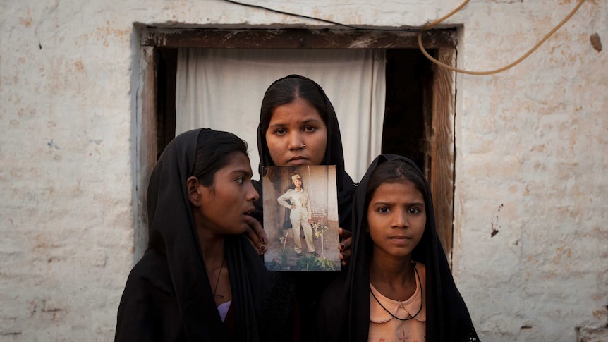 The daughters of Asia Bibi pose with an image of their mother in 2010.