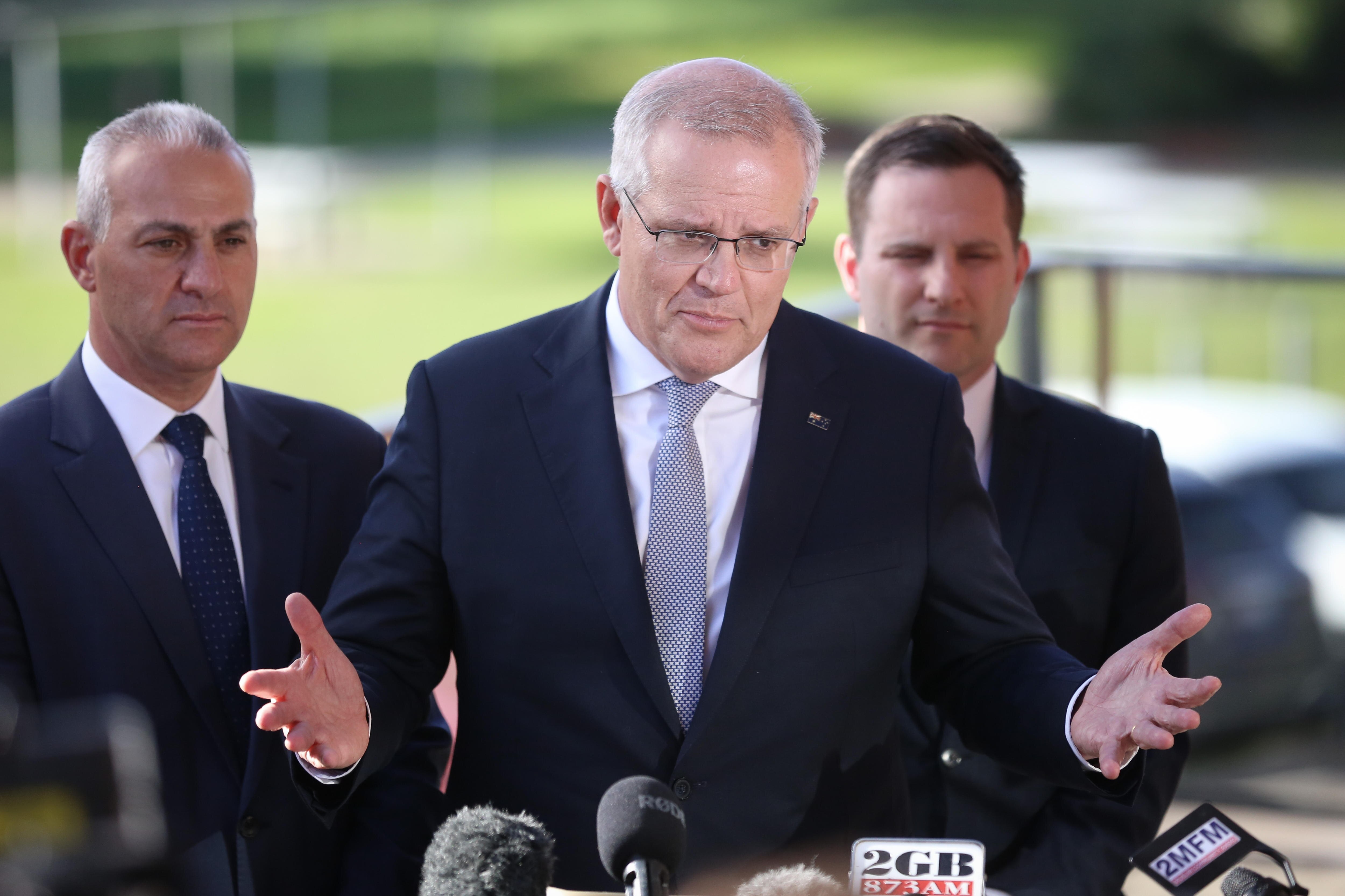 three men wearing suits address the media 