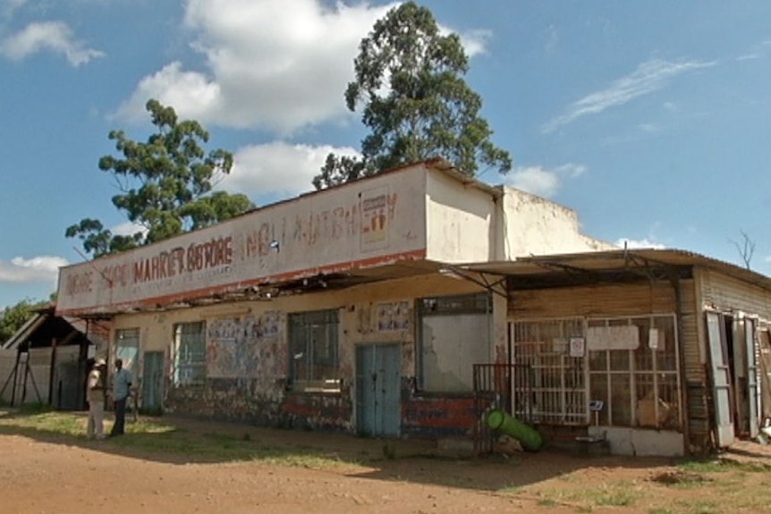 people talk outside a dilapidated local market