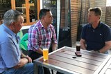 Three men sit at a table at a pub