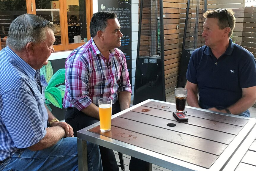 Three men sit at a table at a pub