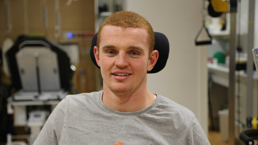 Alex McKinnon sin a room of medical and exercise equipment.