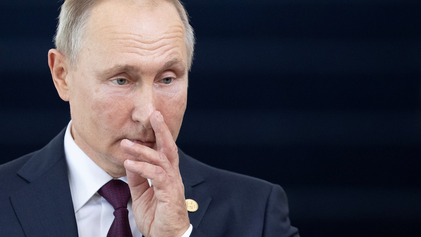 Vladimir Putin touches his face, looking thoughtful