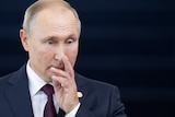 Vladimir Putin touches his face, looking thoughtful
