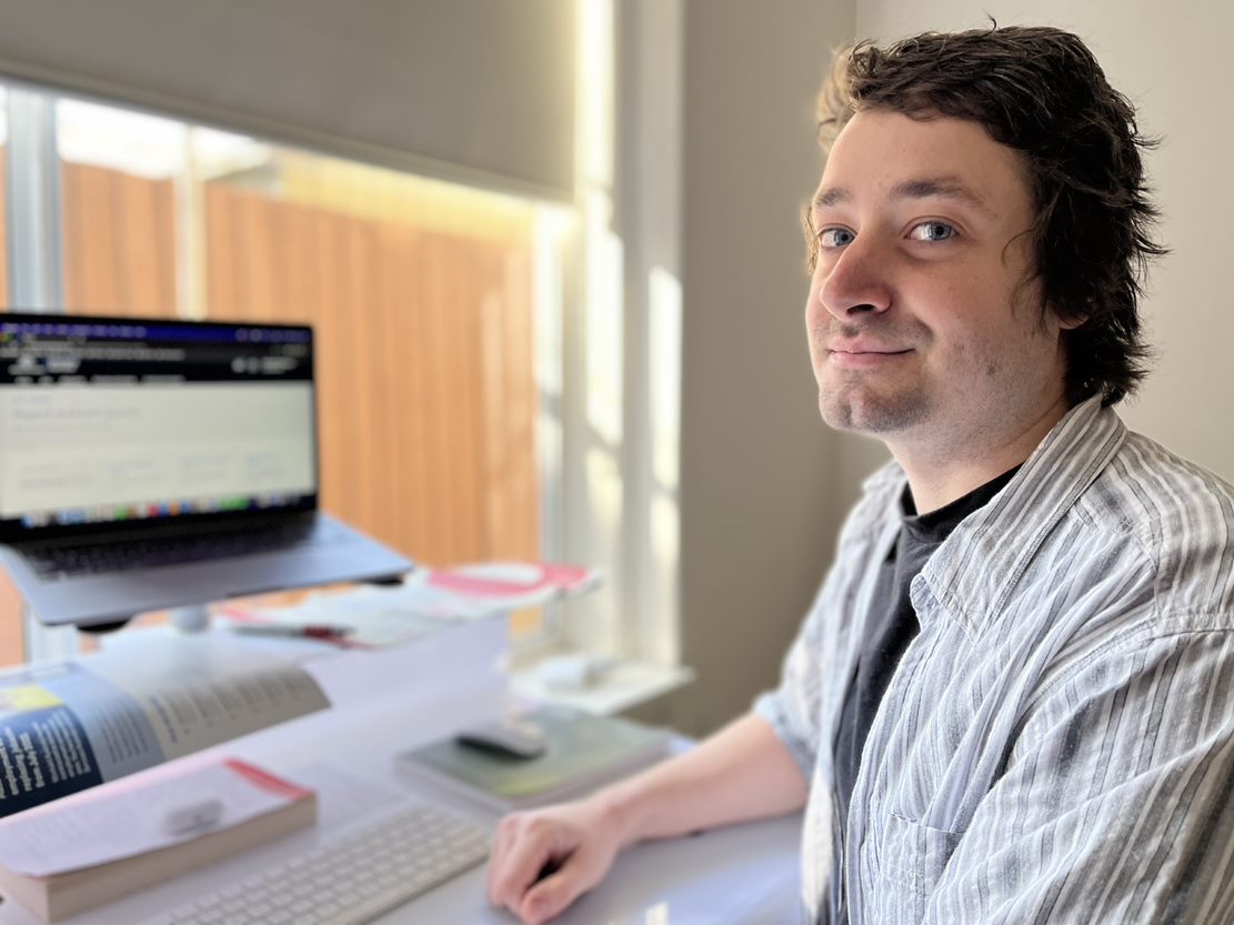 A white man with brown hair sitting at a computer