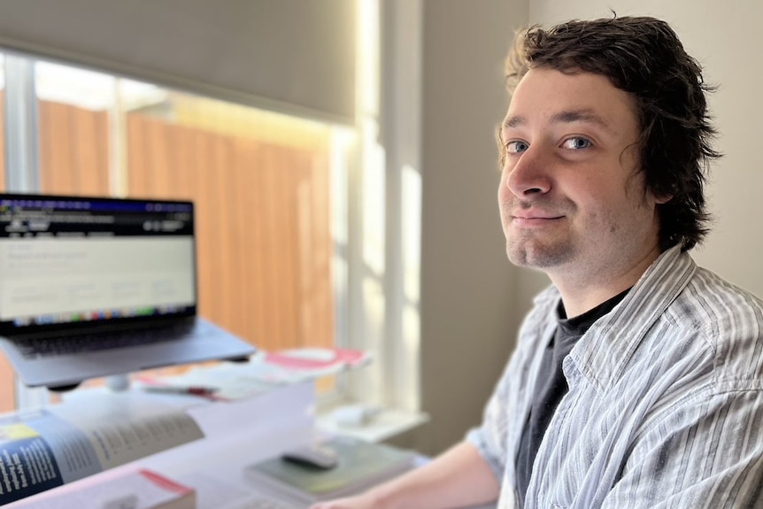 A white man with brown hair sitting at a computer