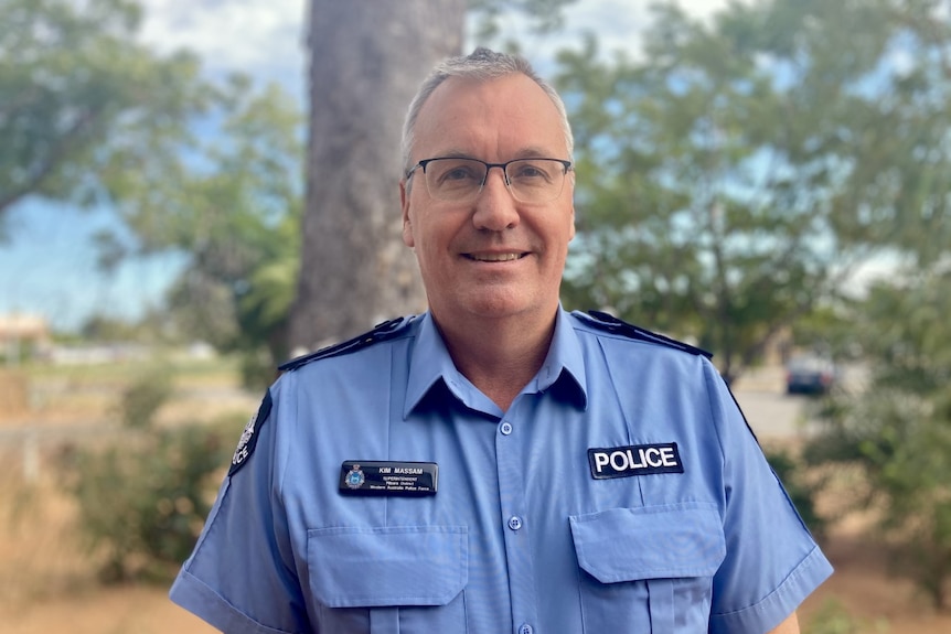 Pilbara Superintendent Kim Massam standing in front of trees and bushes, smiling. 