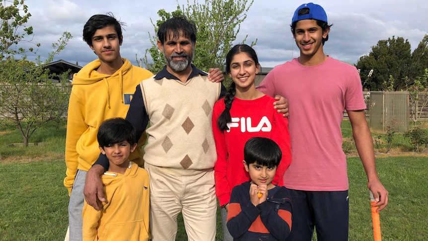 Dr Iqbal Zafar stands outside with five children