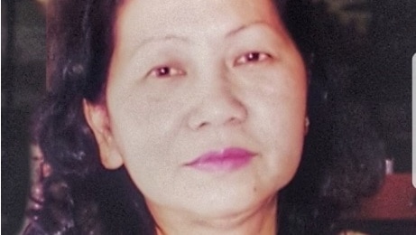 A portrait photograph of Le Ngoc Le who is wearing a gold necklace and black and gold top.