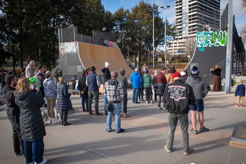 People standing around a large skateboarding ramp. 