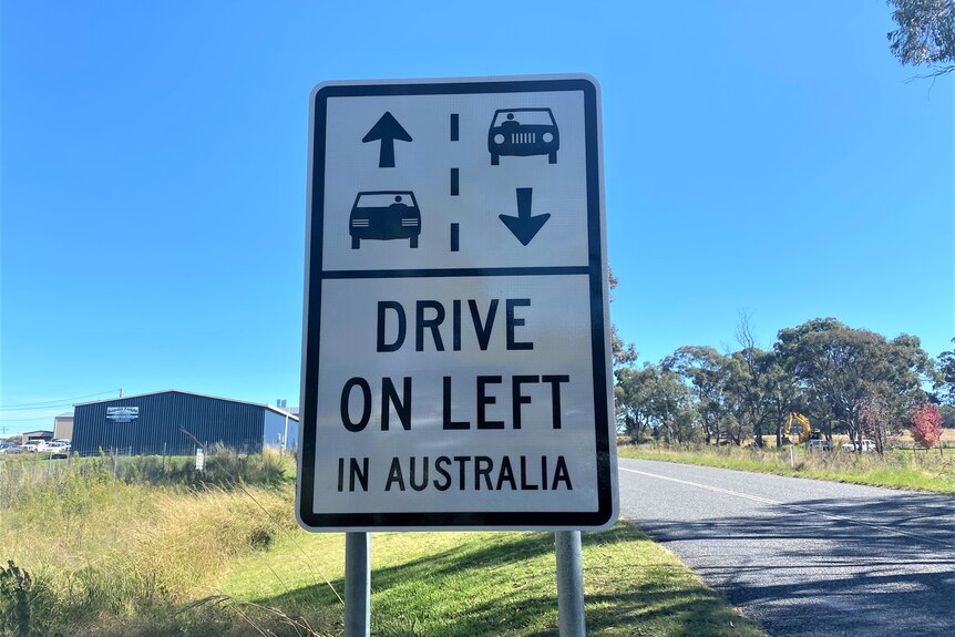 A sign on the side of a highway reads: 'Drive on left in Australia'