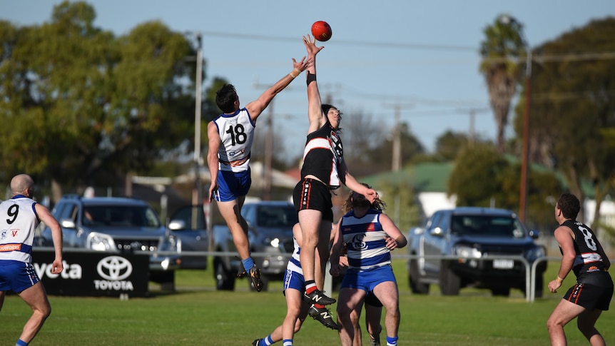 two men playing football jump for ball in ruck