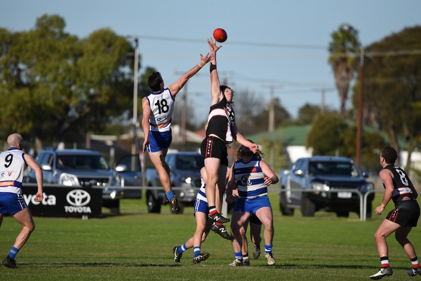 two men playing football jump for ball in ruck