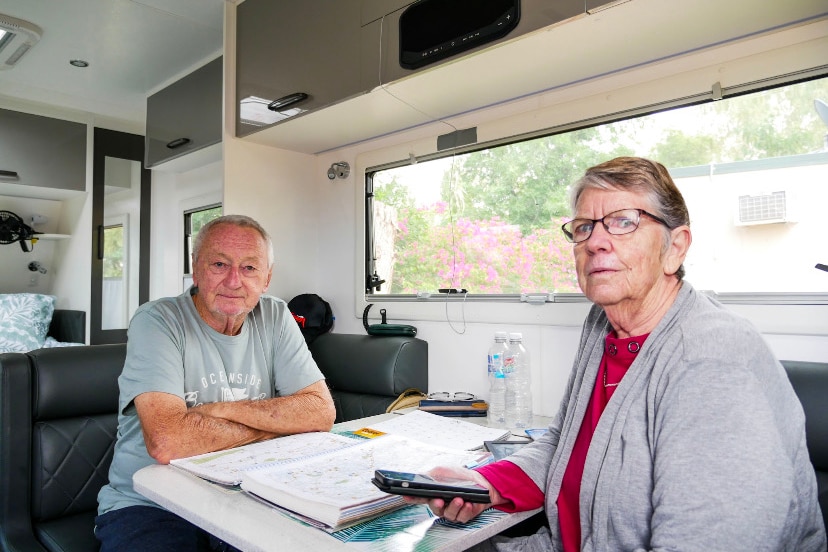 Two older people sit in their RV looking over maps and travel guides. 