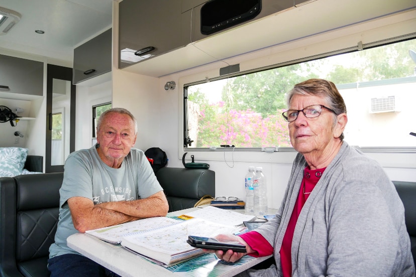 Deux personnes âgées sont assises dans leur camping-car et regardent des cartes et des guides de voyage. 