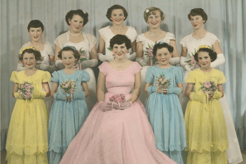 An old photograph of women and girls wearing formal dresses and holding bouquets.