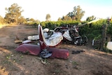A crashed and damaged white and red light plane on the ground