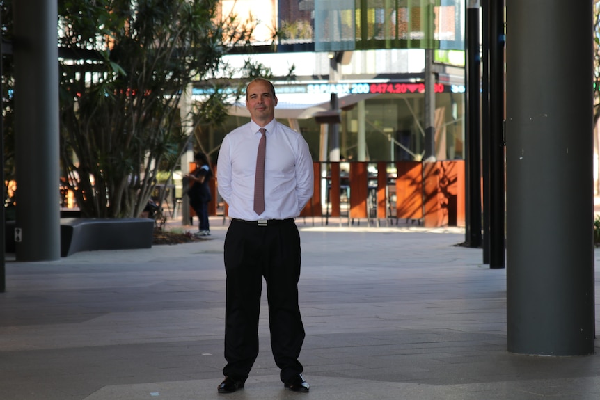 Professor Fitzgerald stands in a university common area, with signage in the background.