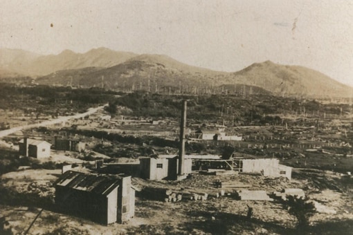A black and white photo of buildings with a mountain range in the background.