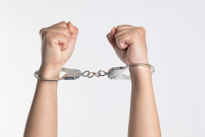 A young person's arms bound in handcuffs