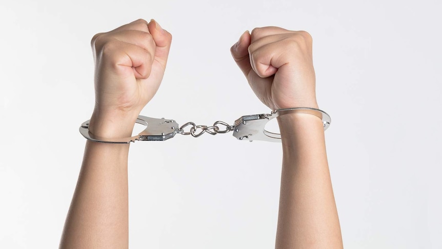 A young person's arms bound in handcuffs