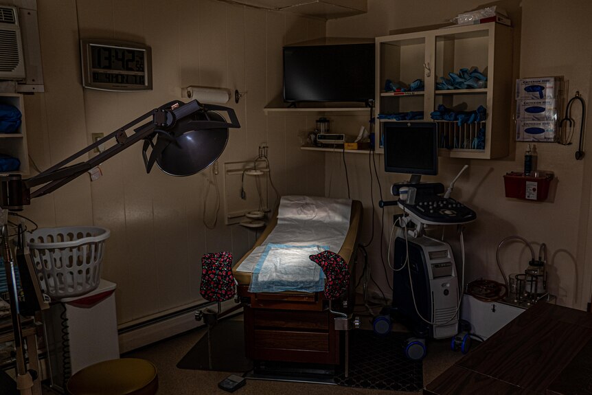 A dark clinic room with a light shining on the bed. 