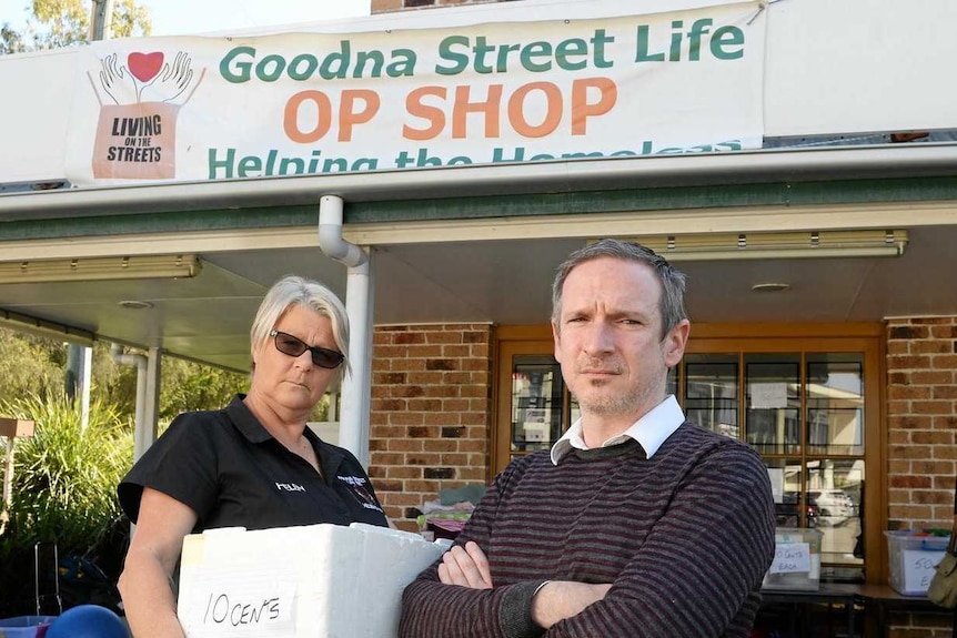 woman holding a bos and man with arms folded in front of Goodna op shop