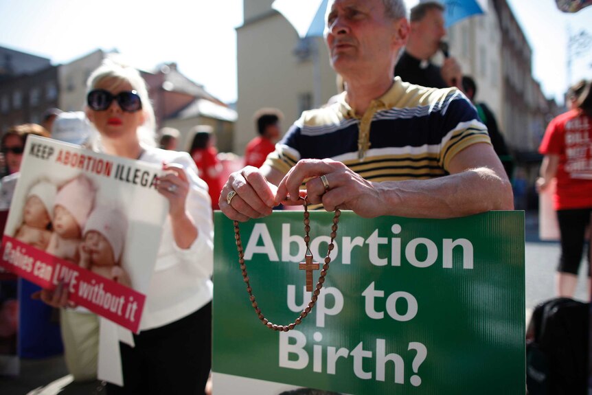 A close shot of of a man and a woman holding anti-abortion placards at a protest rally, 2013.