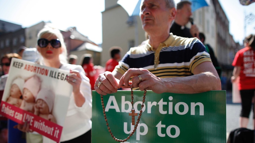 A close shot of of a man and a woman holding anti-abortion placards at a protest rally, 2013.