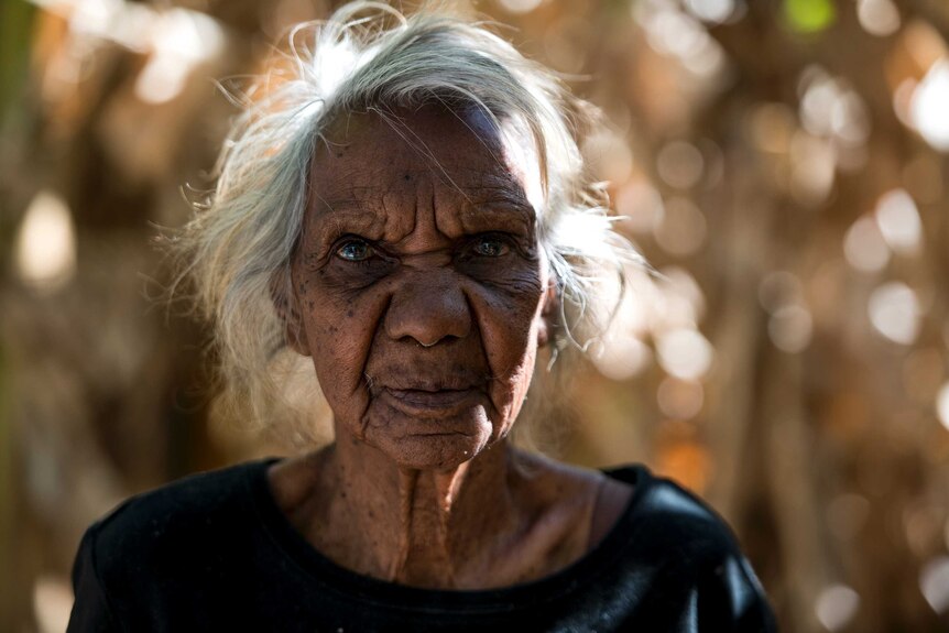 An elderly Aboriginal woman wearing a black tshirt with an out-of-focus background.