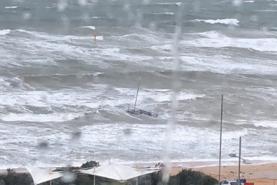 A photo taken from a rainy window shows a piece of a pier sitting in a choppy sea.