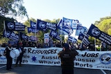 Union workers with flags, drums, loudspeakers and banners blockade a road.