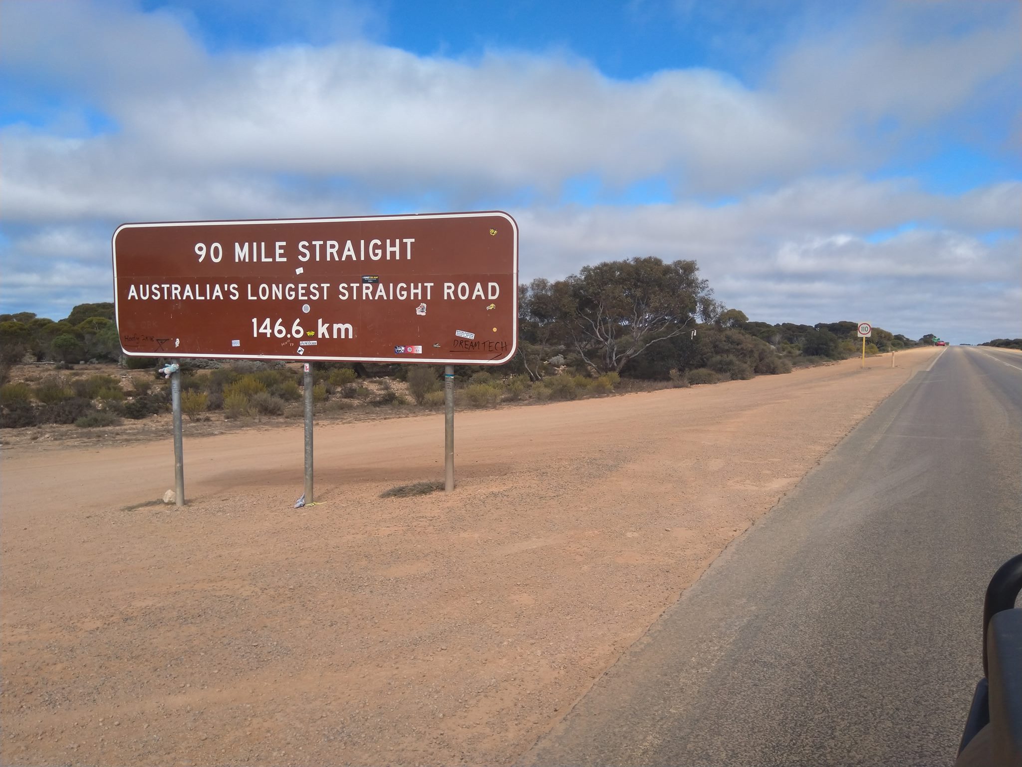 A sign reading "90 Mile Straight" and a road stretching into the distance