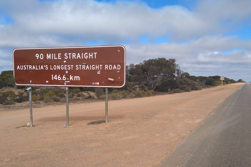 A sign reading "90 Mile Straight" and a road stretching into the distance