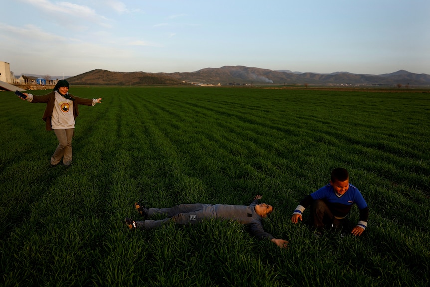 Children play a green field.