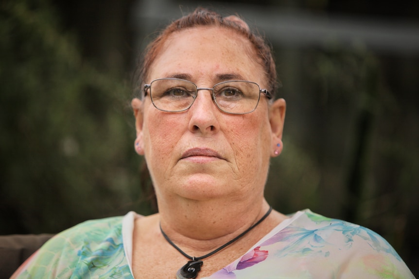 Older woman wearing glasses sitting outside.