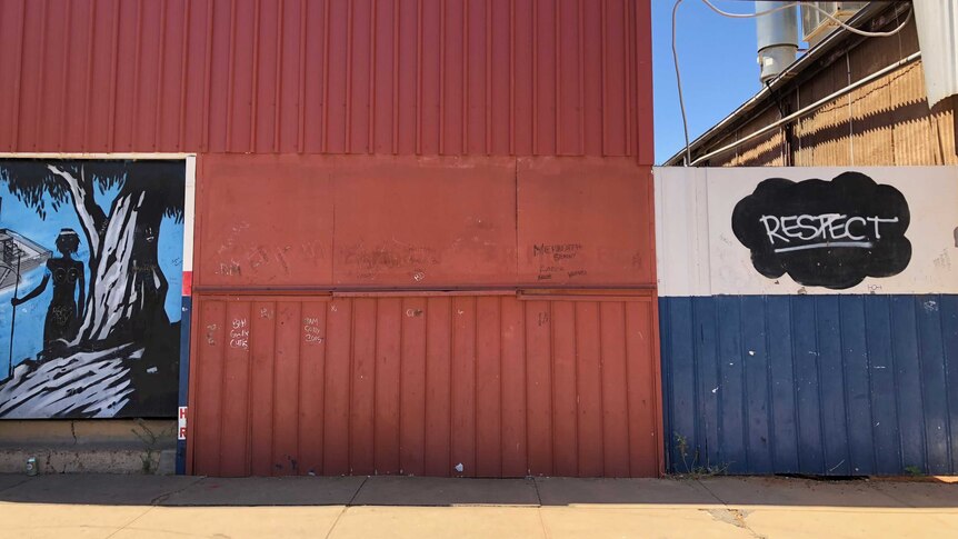 Part of a mural, on the left, and graffiti that says "respect," on the right, on the side of a corrugated wall  in Wilcannia.