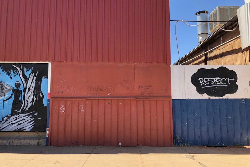 Part of a mural, on the left, and graffiti that says "respect," on the right, on the side of a corrugated wall  in Wilcannia.